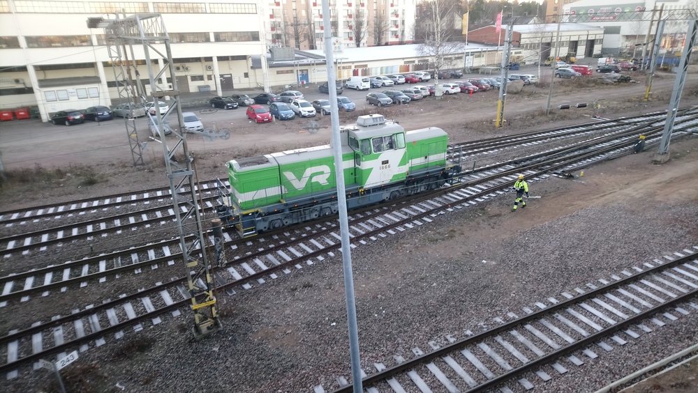 Dr14 Kotkassa 22.11.2018
Dr14 1866 on aloittanut useamman muun dieselveturin kanssa työpäivänsä Kotkan varikolla ja tekee lähtöä aamuvuoroon Mussalon satamaan. Päivystyshommissa oli Kotkassa tuona päivänä niin Dr14- kuin Dv12-vetureitakin, minkä lisäksi Fenniarail teki vaihtotöitä Dr18:lla. Kotkan aseman vaihteet eivät vielä tuohon maailmanaikaan olleet kauko-ohjattuja, joten matka varikolta aseman eteen kävi varsin hitaasti, kun vähän välistä piti pysähtyä odottamaan, että vaihde ehditään käästää nenän edestä.
Avainsanat: op_VR;jt_Vaihtotyö;jyv_Dr14;päivystäjä_Kotka