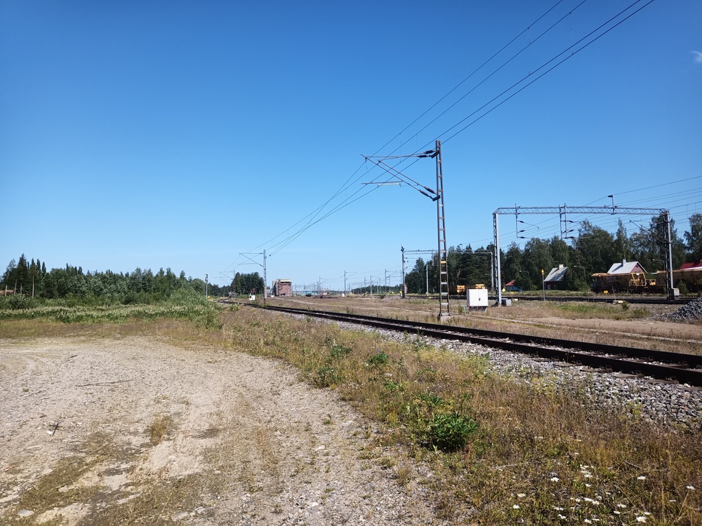 Pieksämäki Temu nähtynä etelästä 4.7.2021
Näkymä Temuun aseman suunnasta. Etualan raide ohittaa varikon sen länsipuolelta. Vasemmalle jää vanha tavara-asema, taka-alalla näkyy liikenteenohjaustorni sekä Temun ratapihalla seisova tyhjä raakapuujuna. Kuvassa oikealla radanpidon käytössä olevaa raiteistoa.

