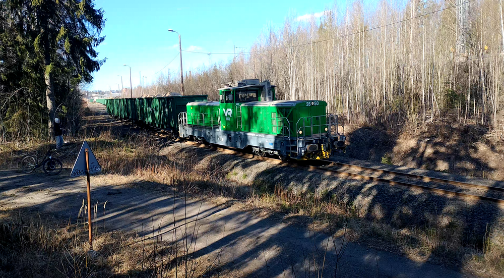 Raasulin haketta 27.3.2026
Viikottainen Riihimäki-Joutseno hakejuna on saanut kunnialla kuormatuksi ja Dr19 numero 2850 on saanut kunnian huolehtia Riihimäen päivystäjän ominaisuudessa pitkähkön puoleisen hakevaunuletkan matkan ensimmäisestä osuudesta terminaalilta ratapihalle. Vaunustonsa puolesta kyseessä on jonkinmoinen anomalia, kyseessä kun on idänliikenteeseen tehdyillä vaunuilla ajettava kotimaan juna.
Avainsanat: op_VR;jt_Vaihtotyö;jyv_Dr19;jyv_Voh;päivystäjä_Riihimäki